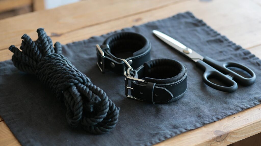 Bondage safety for beginners - Power Play Studio Bondage safety for beginners: coiled black bondage rope, padded leather wrist cuffs and safety shears - Power Play Studio